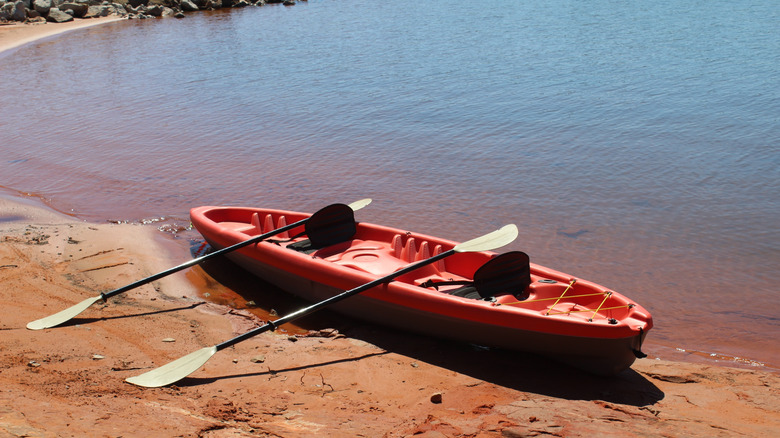 A red kayak on the red sand shore of Lake Stanley Draper in Oklahoma City, Oklahoma