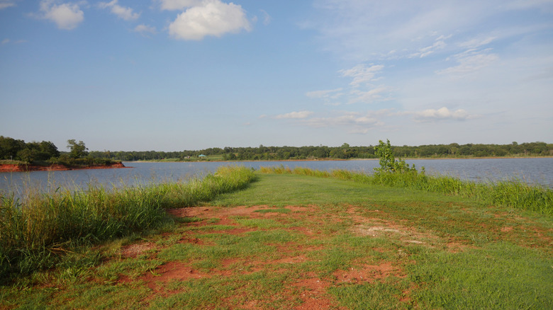 Red soil covered with grass set against the blue waters of Lake Stanley Draper in Oklahoma City, Oklahoma