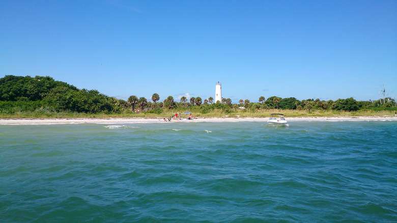 Water with beach and lighthouse in the background