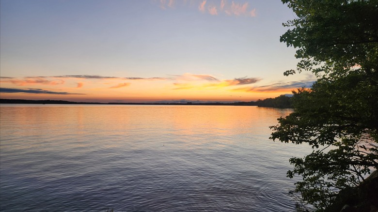 The Lovewell Reservoir at sunset with orange and blue hues reflecting in the water in Lovewell State Park, Kansas.