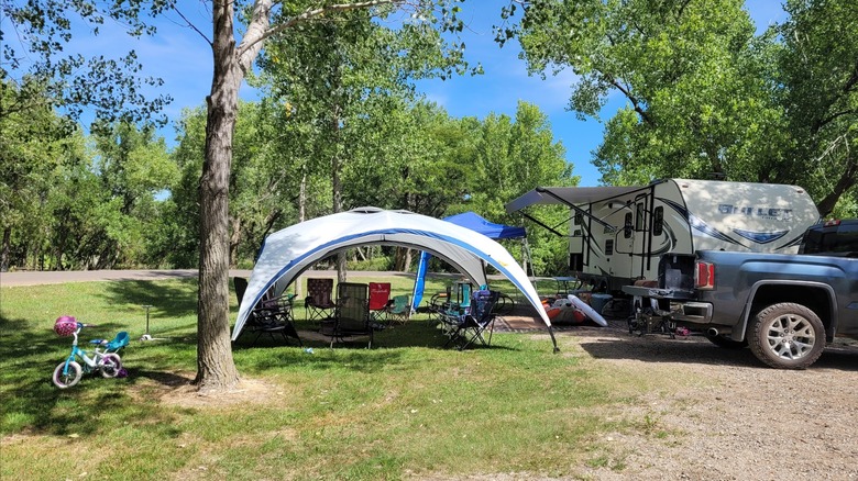 Campsite setup complete with a trailer, canopy tents, and chairs at Lovewell State Park, Kansas