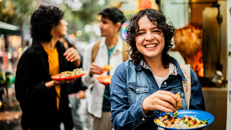 Young woman eating tacos on the street
