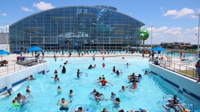 A water park with an outdoor pool and slides housed within a glass building.