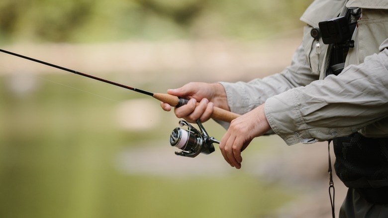 Close-up of a fisherman casting a line near a lake