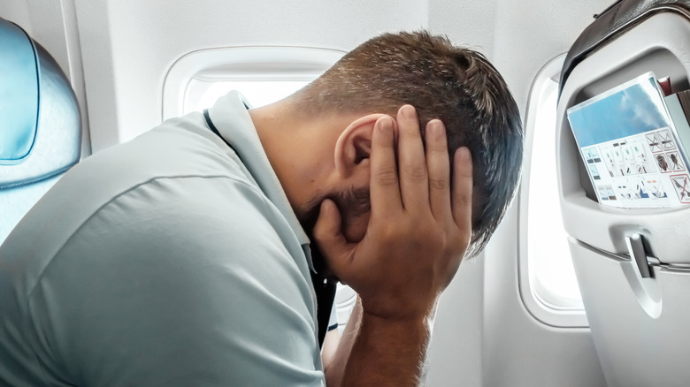 A man covers his ears on a flight