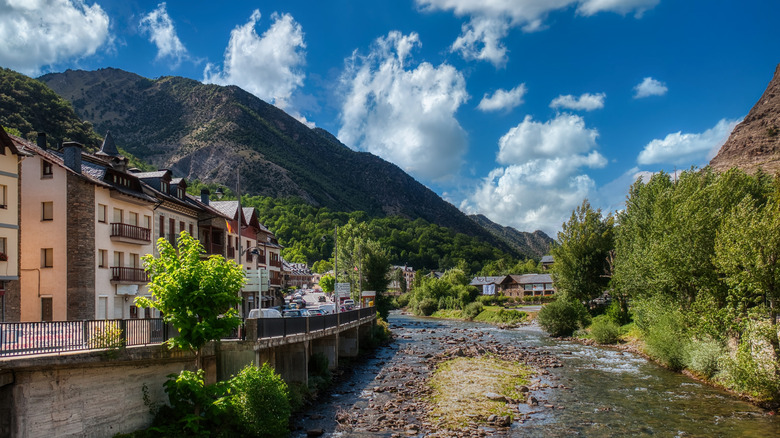 A river alongside quaint buildings in front of a mountain in Llavorsí, Spain
