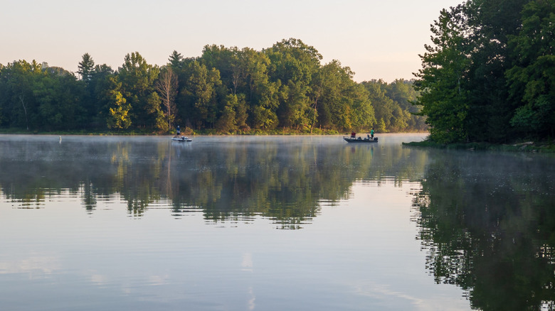 Calm lake at Kincaid Lake State Park, with light morning mist and small boats drifting near the tree-lined shore