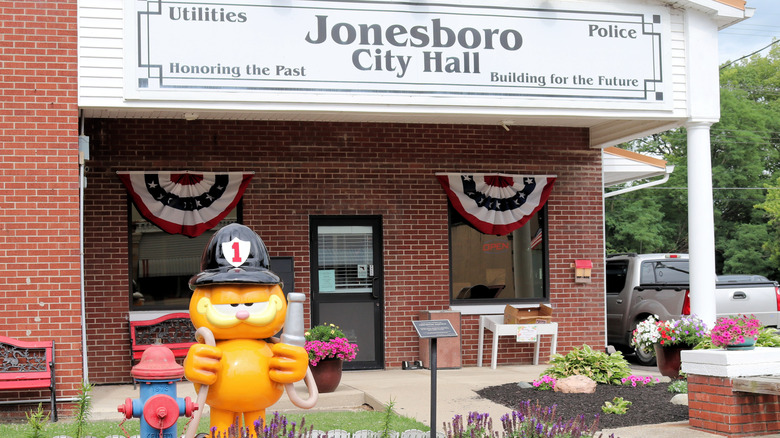 A colorful statue of the cartoon cat Garfield dressed as a fireman in front of Jonesboro Indiana City Hall