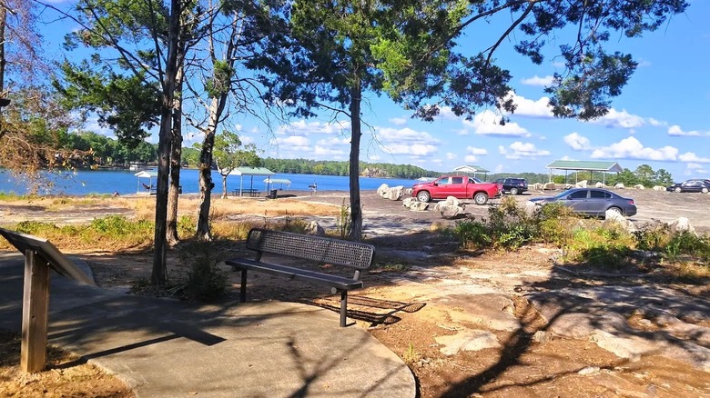 Views of a lakefront park in Lineville, Alabama, featuring blue waters, trees, parked cars, and picnic spots.