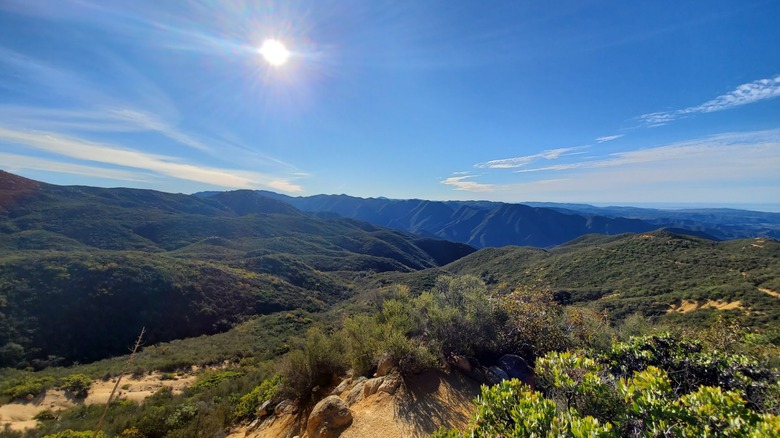 Panoramic mountain views from Caspers Wilderness Park in Southern California, with rugged green hills stretching beneath a bright blue sky