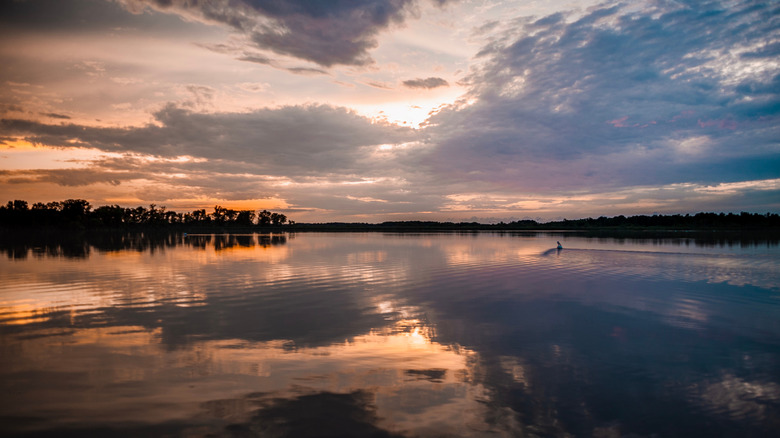 Sunset over Lake Osakis during a cloudy day with trees in the distance.