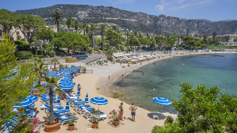 Plage des Fourmis in Beaulieu-sur-Mer, French Riviera, with palm trees and blue-and-white parasols