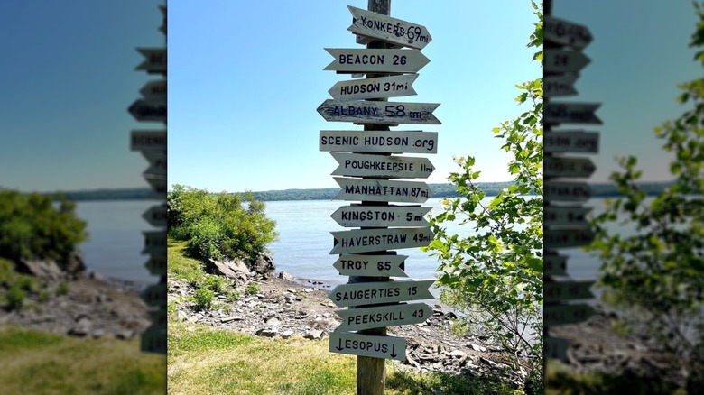 A rustic sign listing distances to nearby towns.