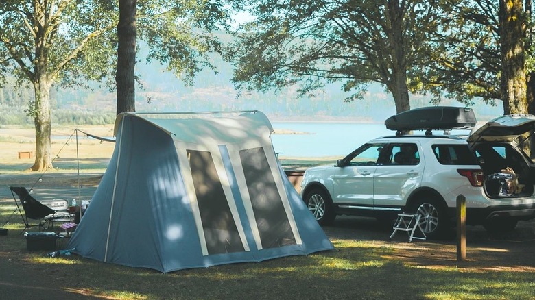 A tent beside an SUV with a lake in the background