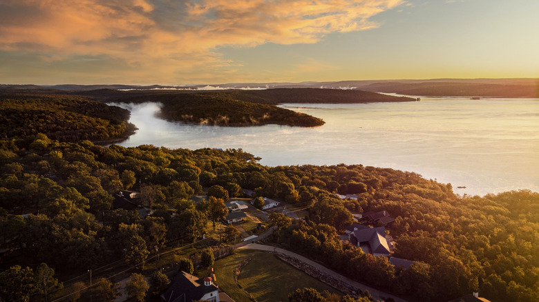 The sunsets over Lake Tenkiller surrounded by tree-covered shores in Oklahoma.