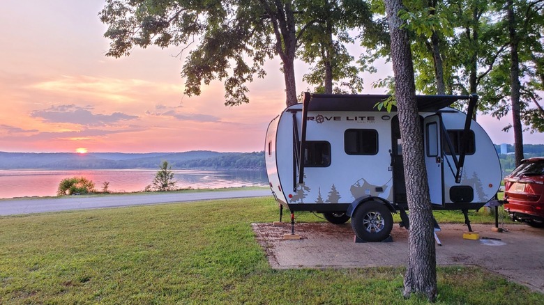 A camping trailer parked in a grassy waterfront campsite at Cherokee Landing State Park at sunset.