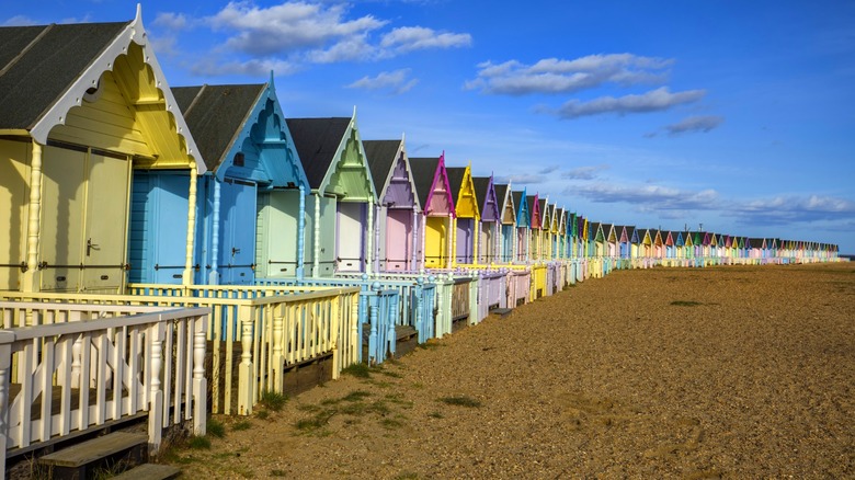 Colorful beach huts lined up on the sand and shingle beach on Mersea Island, Essex, England