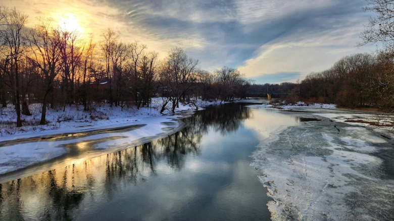 A river party frozen over with snow on the banks, winter in Marott Woods Nature Preserve at sunset