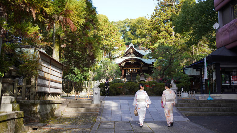 Two women dressed in kimonos walk in front of the Okazaki Shrine in Kyoto, Japan