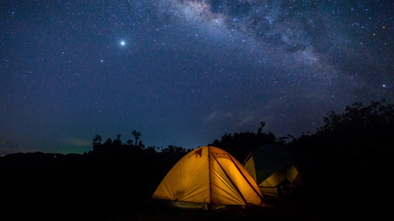 A tent glowing surrounded by starry skies