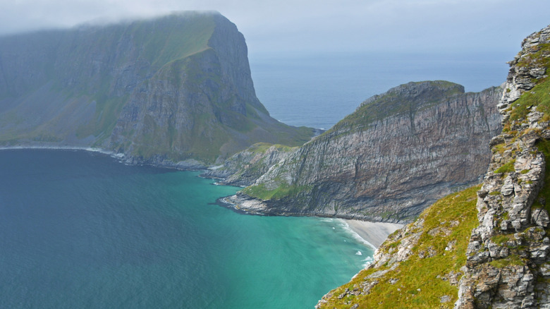 An aerial view of Puinn Sand beach peeking out behind a cliff