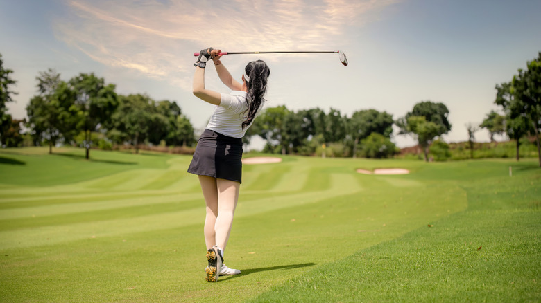 Woman in white top and skirt playing golf