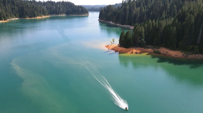 A single watercraft on the emerald-green waters of the Sly Creek Reservoir.