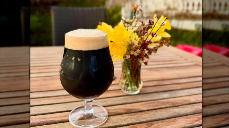 Glass of beer and flowers on a wood table