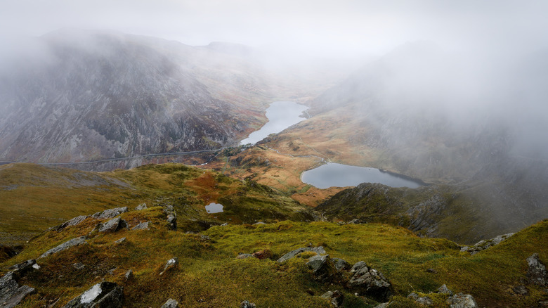 The lake of LLyn Idwal appears through the clouds from a path on the mountain above