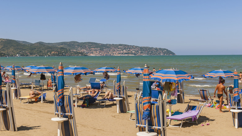 Beach umbrellas and sunbathers on sandy beach