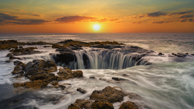 Water rushes into Thor's Well in the Pacific Ocean at sunset in Oregon