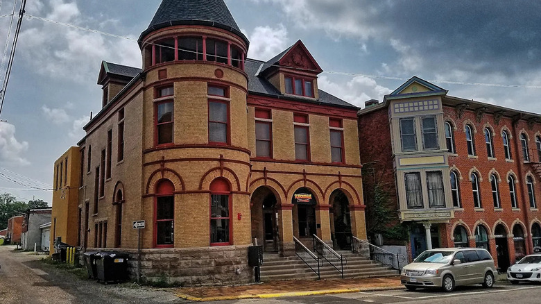 Victorian architecture of Fort Madison, Iowa demonstrated in two side-by side buildings; one has a castle-like appearance and the other is red brick with a van parked on the street out front