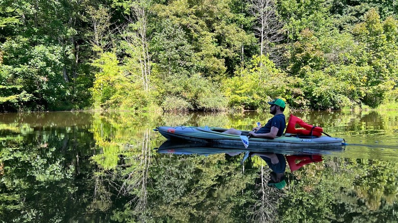 Man kayaking at Forked Run State Park, Ohio, with the water reflecting the scenery