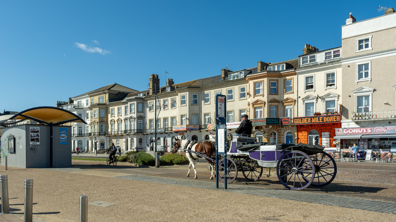 A horse-drawn carriage rolls past beachside businesses on a sunny day in Great Yarmouth, UK