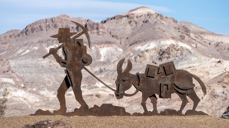 A metal sculpture of a miner and a burro