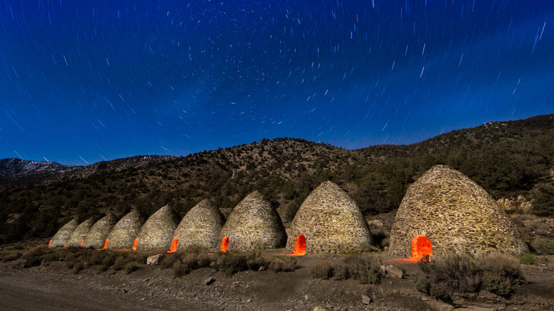 Beehive-shaped ovens lit up at night with stars behind them