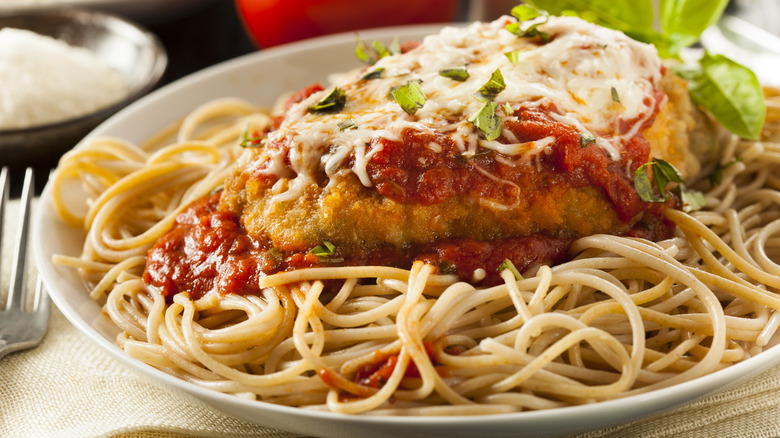 A plate of chicken parmigiana on spaghetti