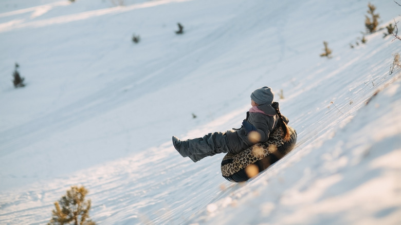 A small child tubing down a hill in the winter