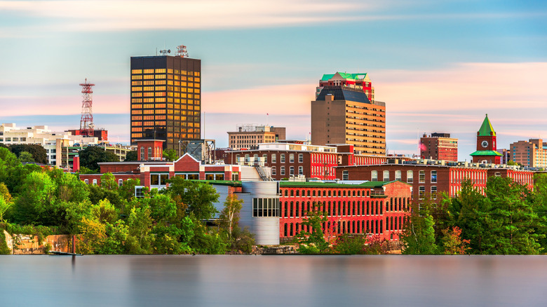 Skyline of Manchester, New Hampshire, during sunset with the Merrimack River in the foreground