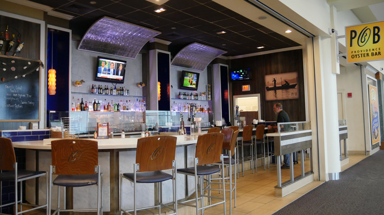 A bar at Rhode Island T.F. Green International Airport with bar chairs and widescreen TVs.