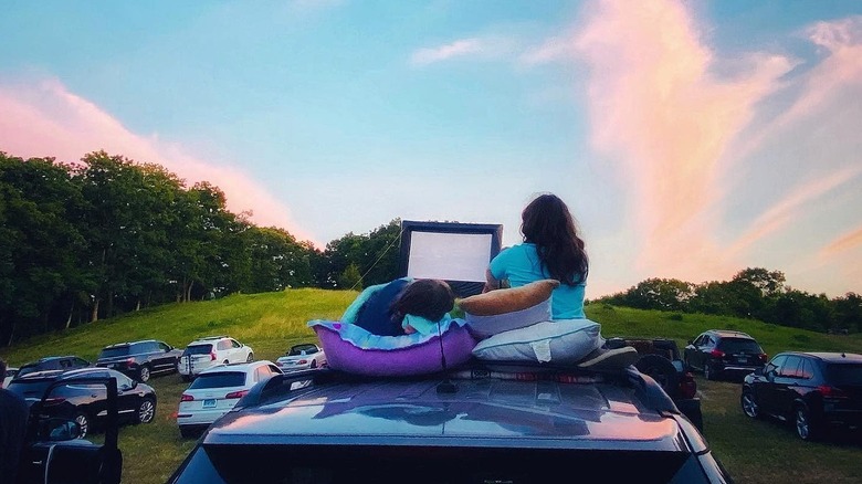 Two people sitting on a car at Mansfield Drive-in Theatre in Mansfield, Connecticut
