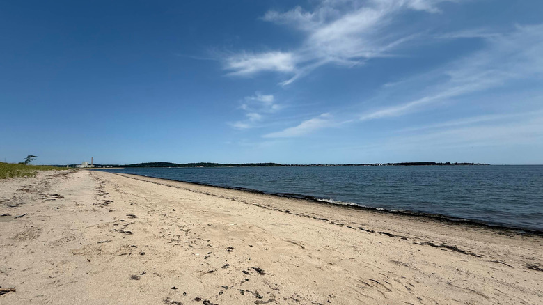 A slate blue ocean sites beside a golden-sand beach at Sandy Point in West Haven, Connecticut