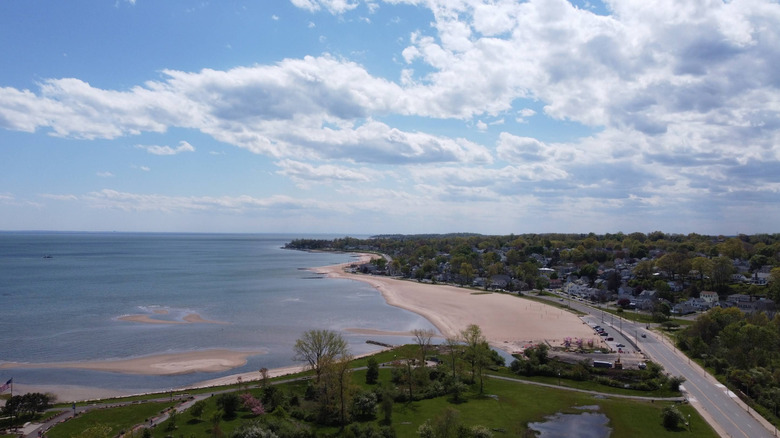 Aerial view of the pale sands and blue water at Bradley Point Beach in West Haven, Connecticut, below a sky with puffy white clouds