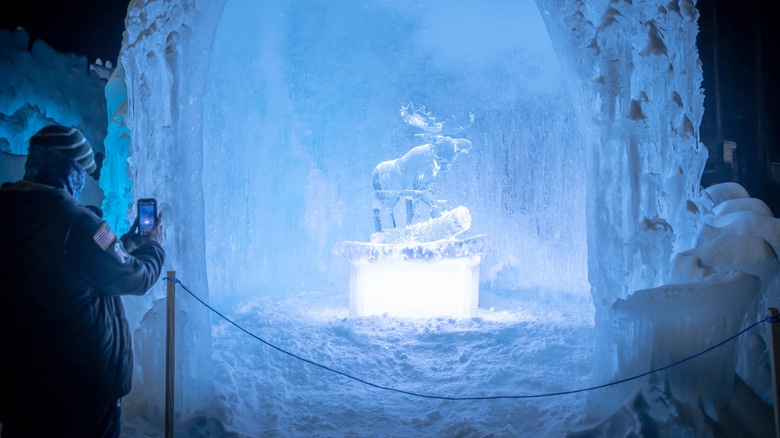 Person taking a picture of an ice statue of a moose at Ice Castles, New Hampshire