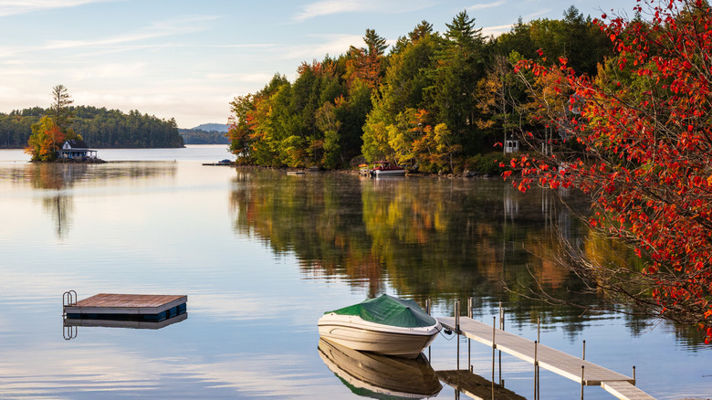 Fall foliage surrounding a boat, diving platform, and house on an island at Newfound Lake near Hebron, New Hampshire