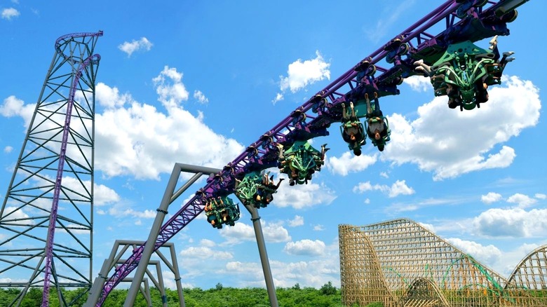 A rendering of a new purple roller coaster and its track with digital people hanging upside down on the ride