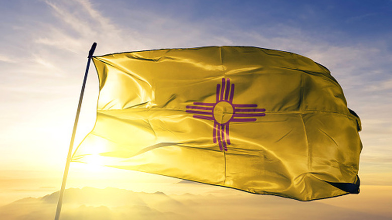 The New Mexico state flag with the sun shining behind it