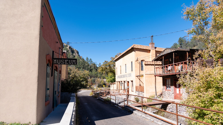 Mogollon ghost town, with tan buildings along a street under a blue sky and a mountain in the background