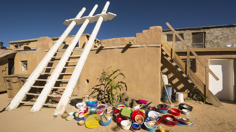 Acoma Pueblo structure and large, white ladder with pottery sitting underneath