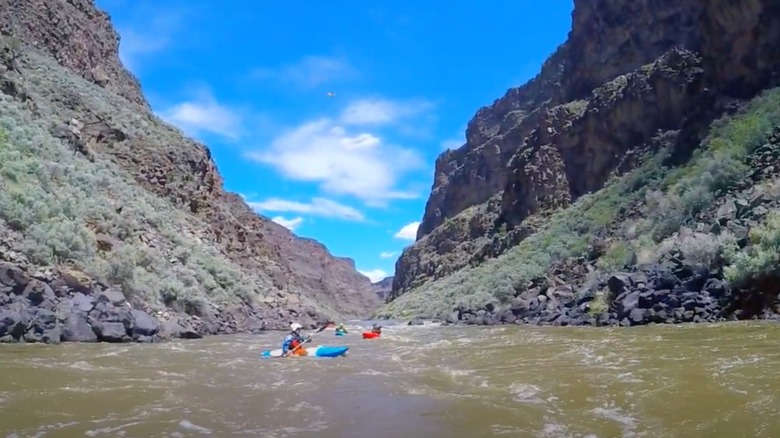 Kayakers on the Rio Grande surrounded by high cliffs blue sky